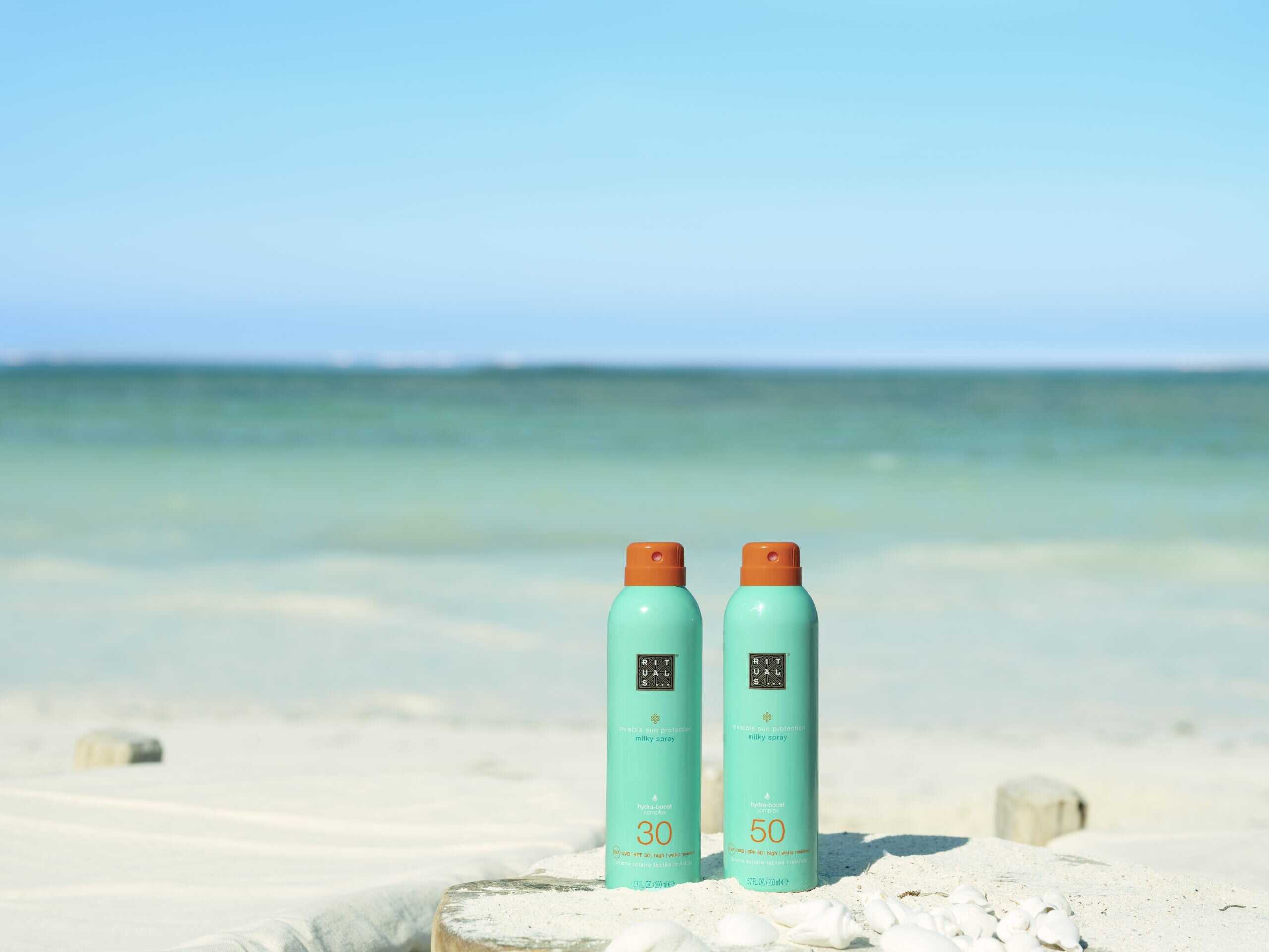 Summer beauty essential for beach-ready skin: Rituals sun milk sprays SPF 30 and 50, shot by the sea.