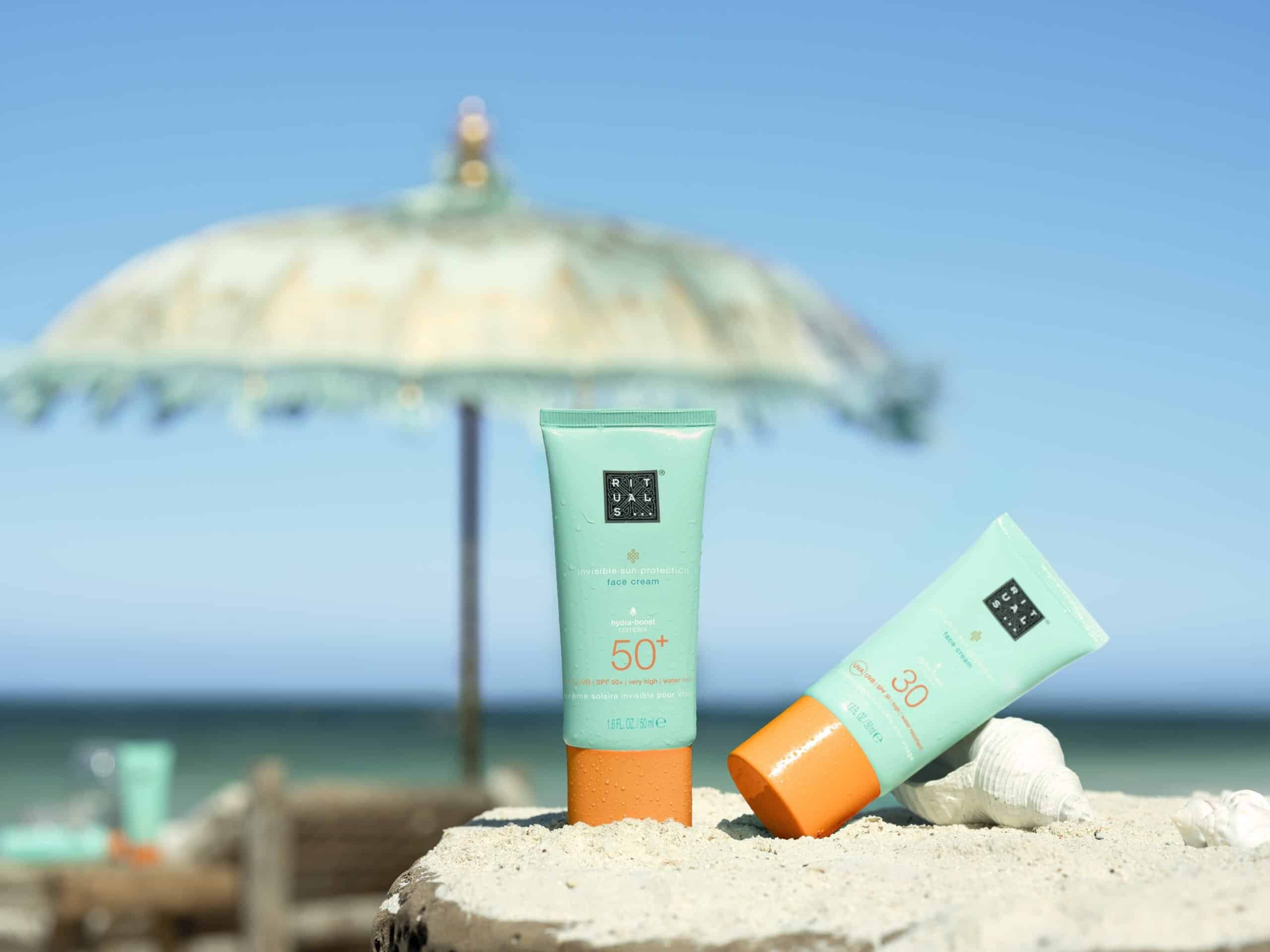  Face suncare essentials from Rituals under a beach umbrella: SPF 30 and SPF 50+ creams.