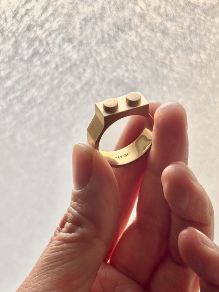 Hand holding a Studio GOGO silver ring inspired by Lego bricks, blending playful design with refined craftsmanship.