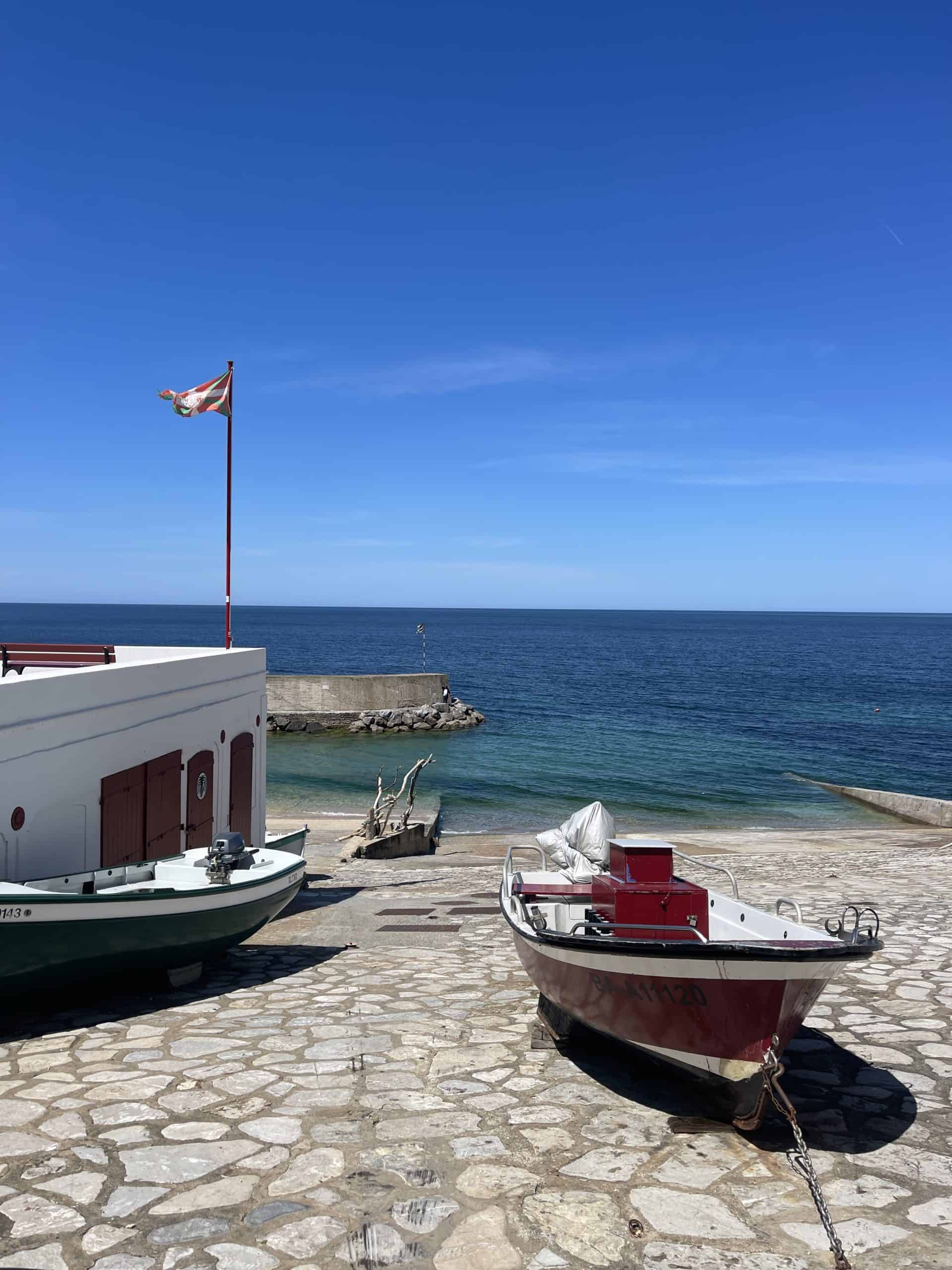 Boats docked on stone pier with ocean horizon 