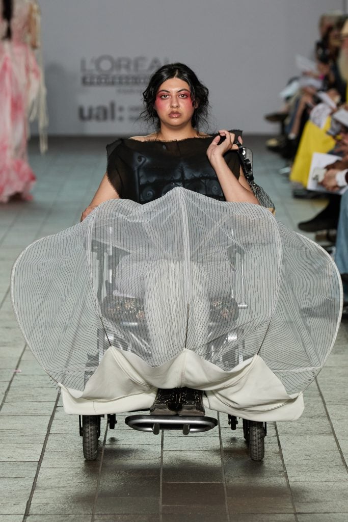 A model in a wheelchair wears a voluminous mesh skirt designed by Hannah Smith during Graduate Fashion Week.