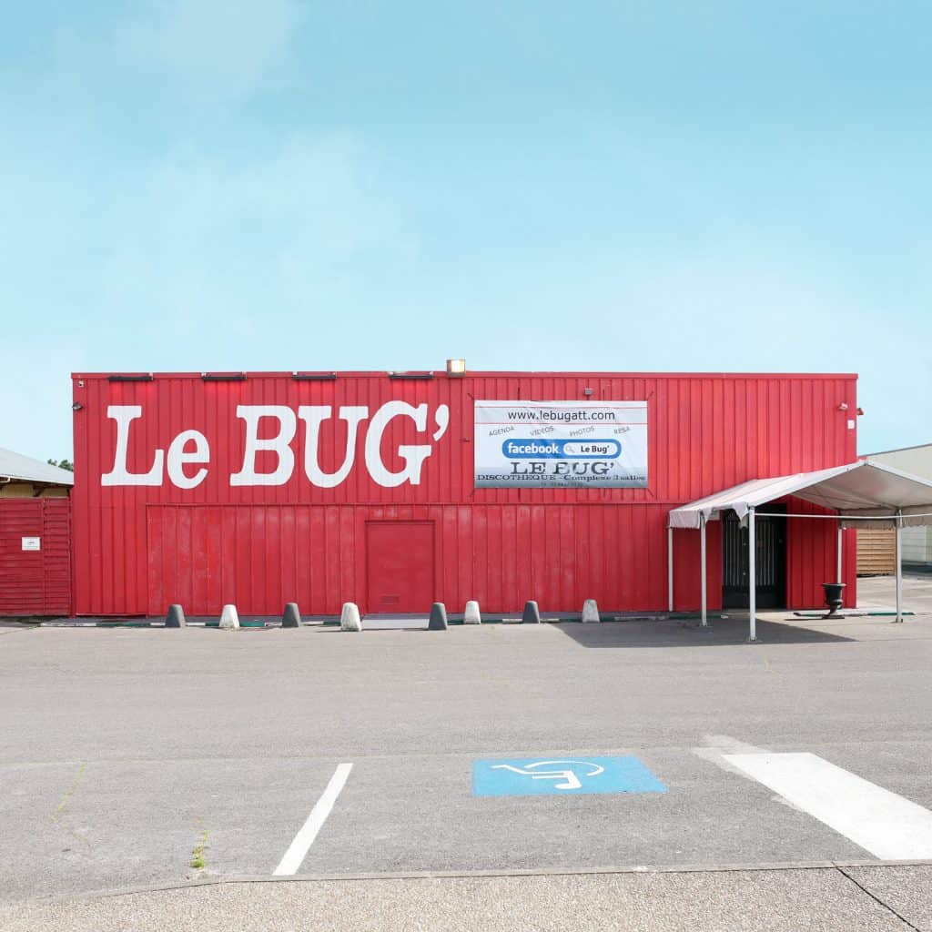Red shipping-container-style facade of Le Bug’ nightclub, seen from an empty parking lot. AFTER PARY 