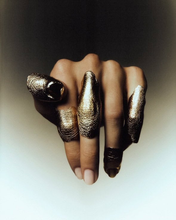 Hand wearing gold-cast fingertip rings by Incarnem, highlighting the texture and individuality of each piece.