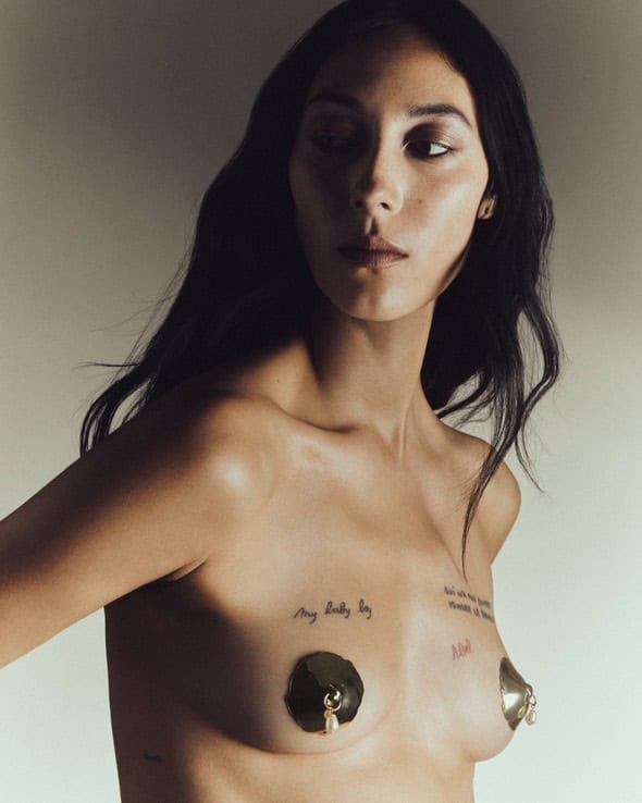 Woman wearing Incarnem's custom nipple jewellery, paired with tattooed script on her chest.