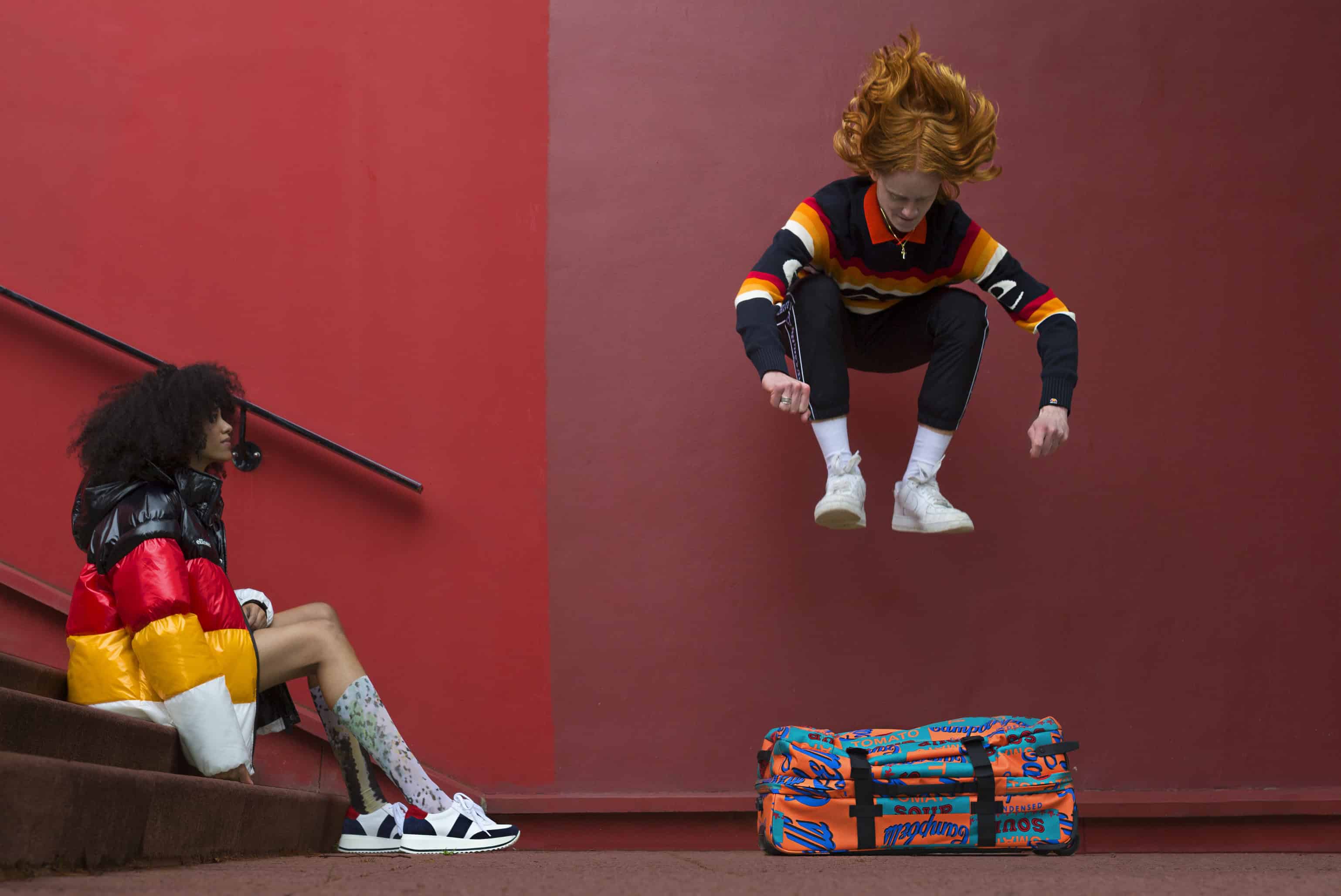 Him: Polo shirt FRED PERRY, sweater & jogging pants ELLESSE, Campbell collaboration suitcase EASTPAK. Her: puffy jacket ELLESSE, serpent print socks WOLFORD, white & navy sneakers BORDEN.