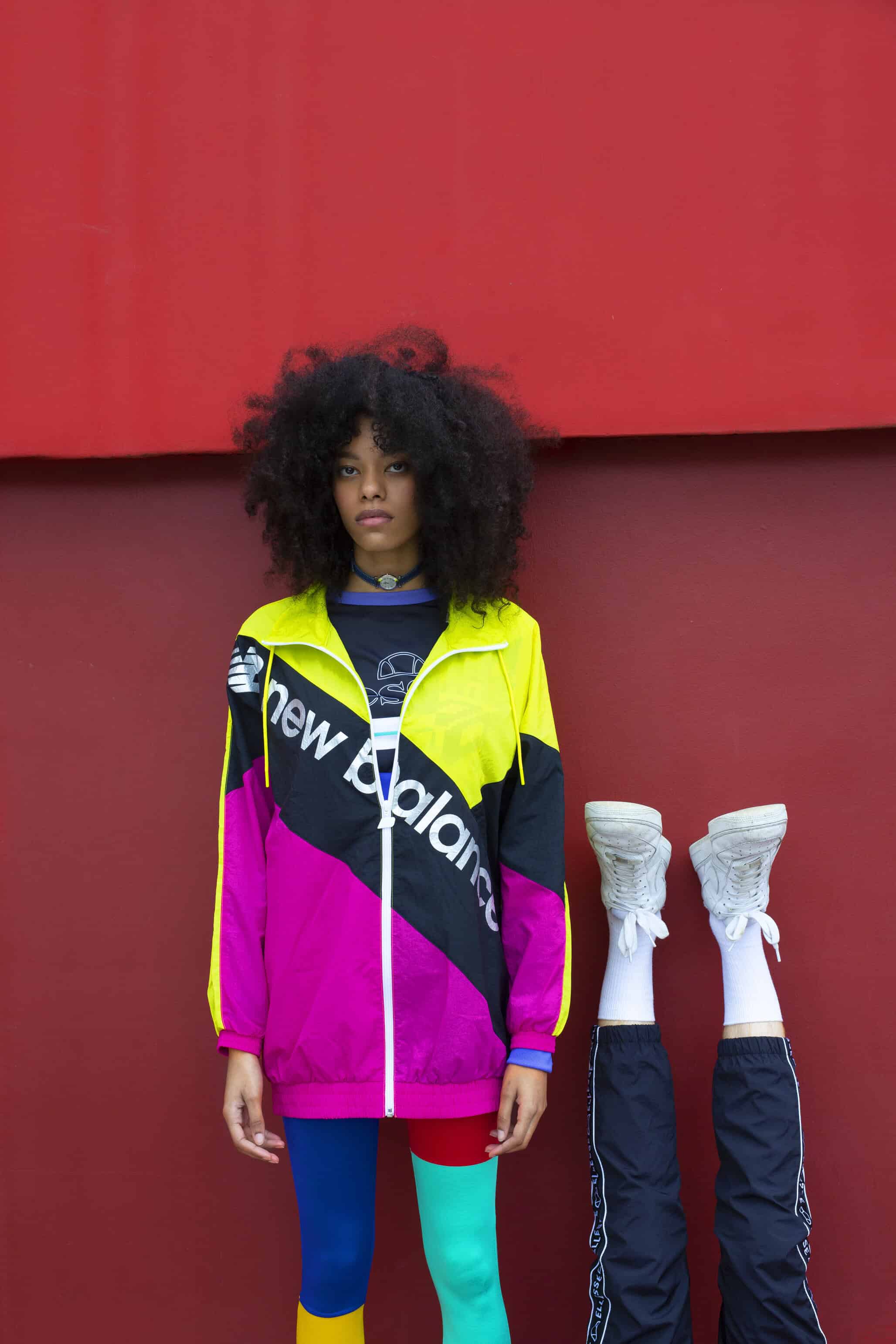Denim strap watch worn around her neck MICHEL HERBELIN, crop top & black jogging pants ELLESSE, windbreaker NEW BALANCE.Him: Black jogging pants ELLESSE.