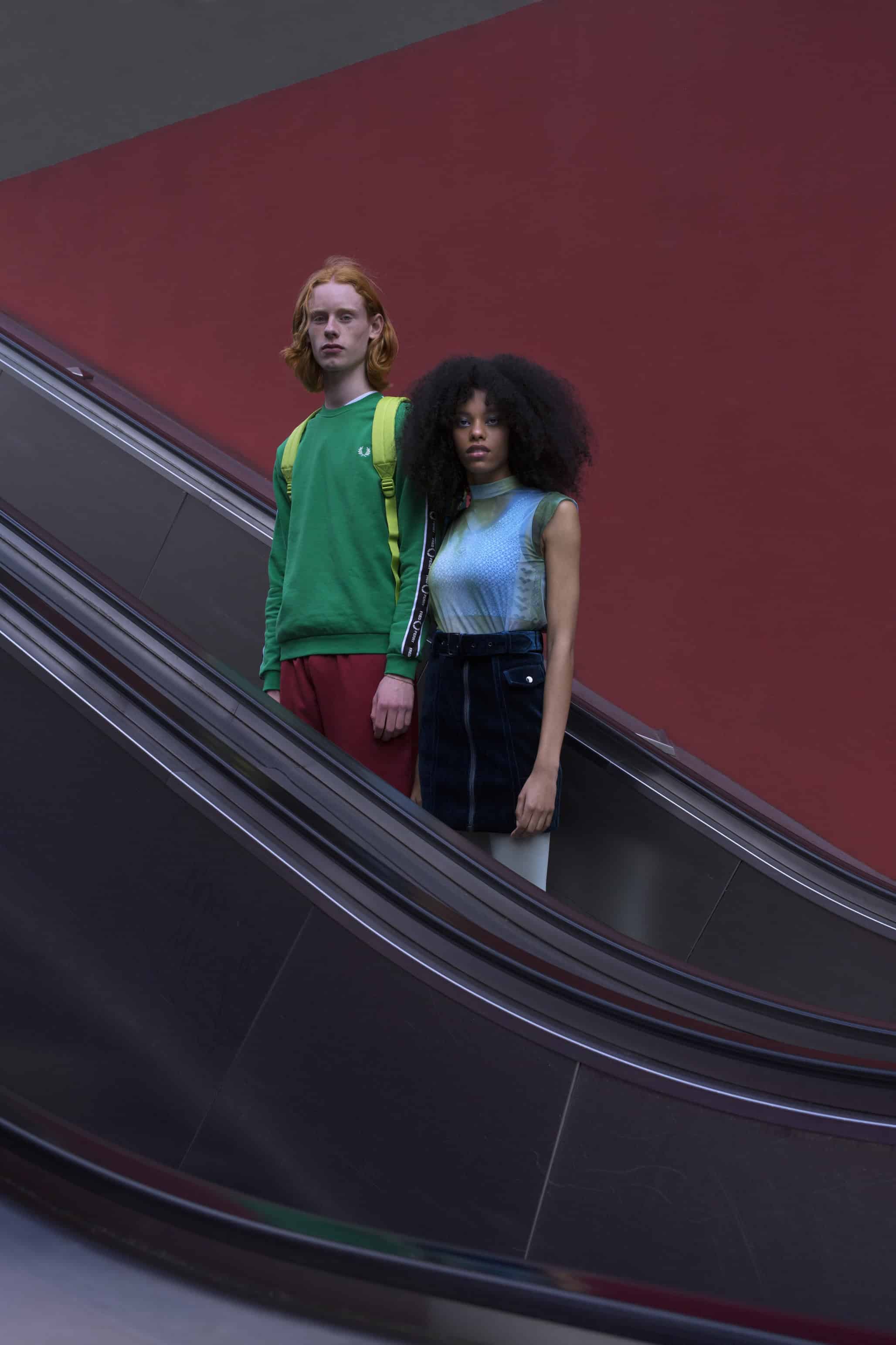 Him: Green sweatshirt with logos on sleeves FRED PERRY, backpack EASTPAK, burgandy jogging pants BEN SHERMAN. Her: Ocean blue velvet skirt MOLLY BRACKEN, jellyfish body suit WOLFORD, logo print sports bra ARENA.