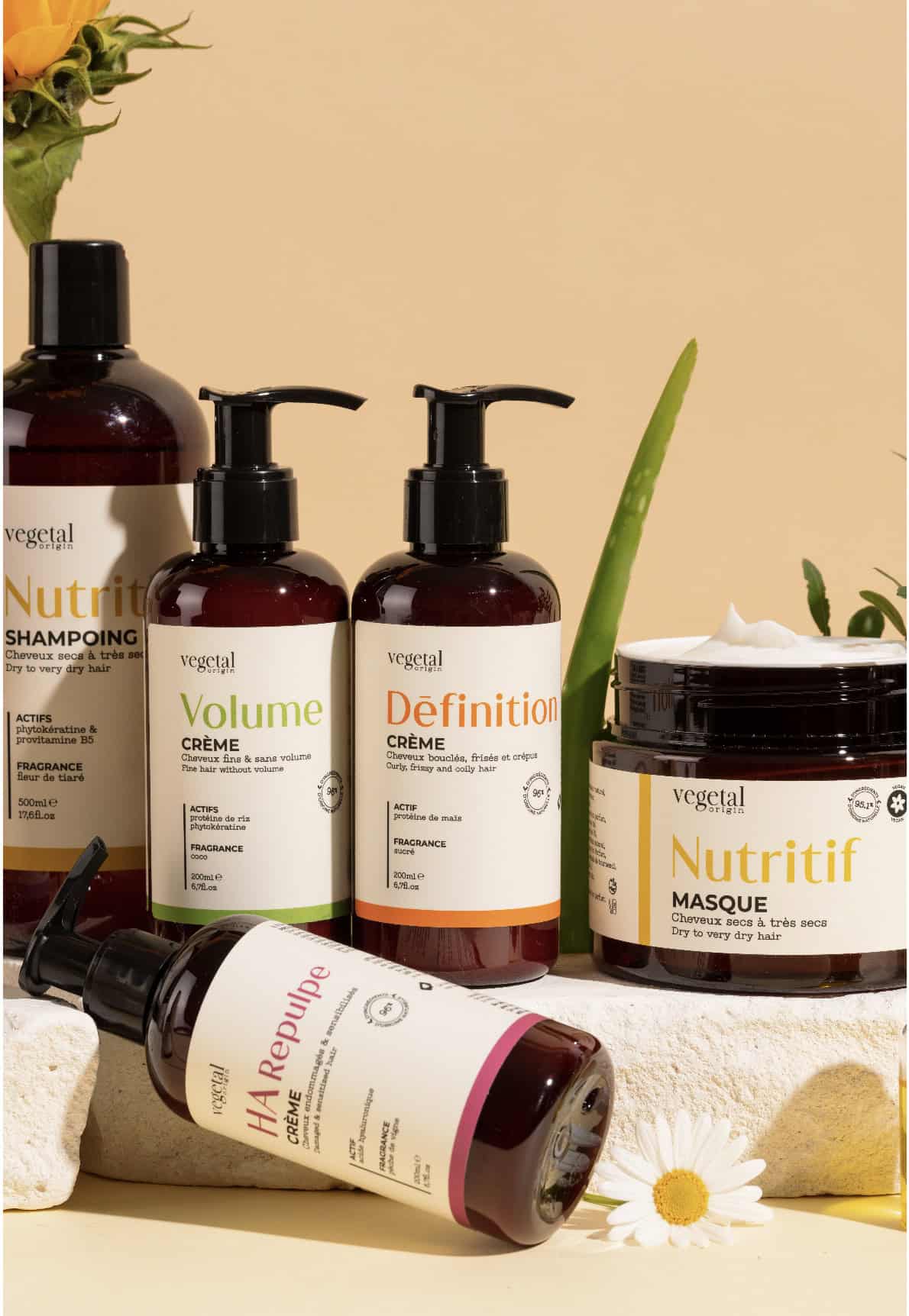  Close-up of Vegetal Origin shampoos, conditioners, and hair masks displayed with natural flowers.