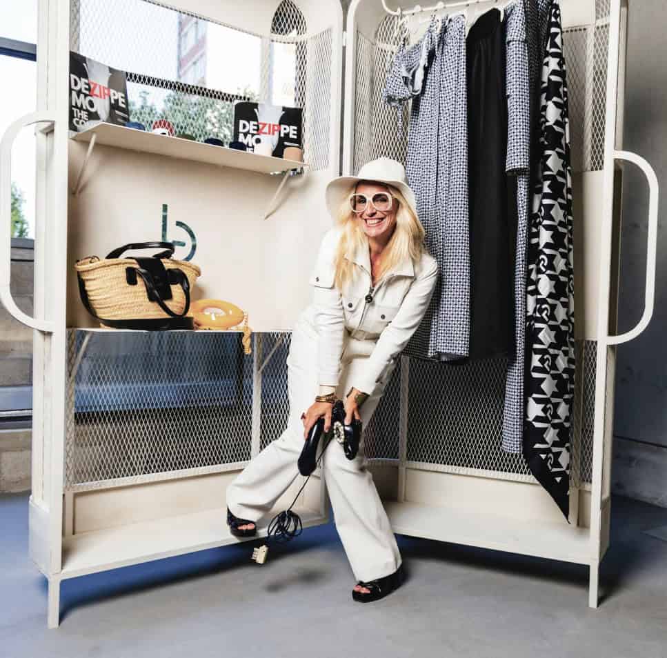 Carolina posing in front of La Malle, wearing a white jumpsuit and sunglasses, embodying her brand’s nomadic spirit.