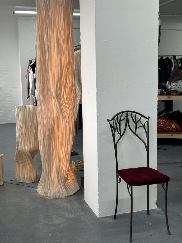 Wooden light sculpture and red chair at APOC store, blending furniture and art in an industrial gallery setting.