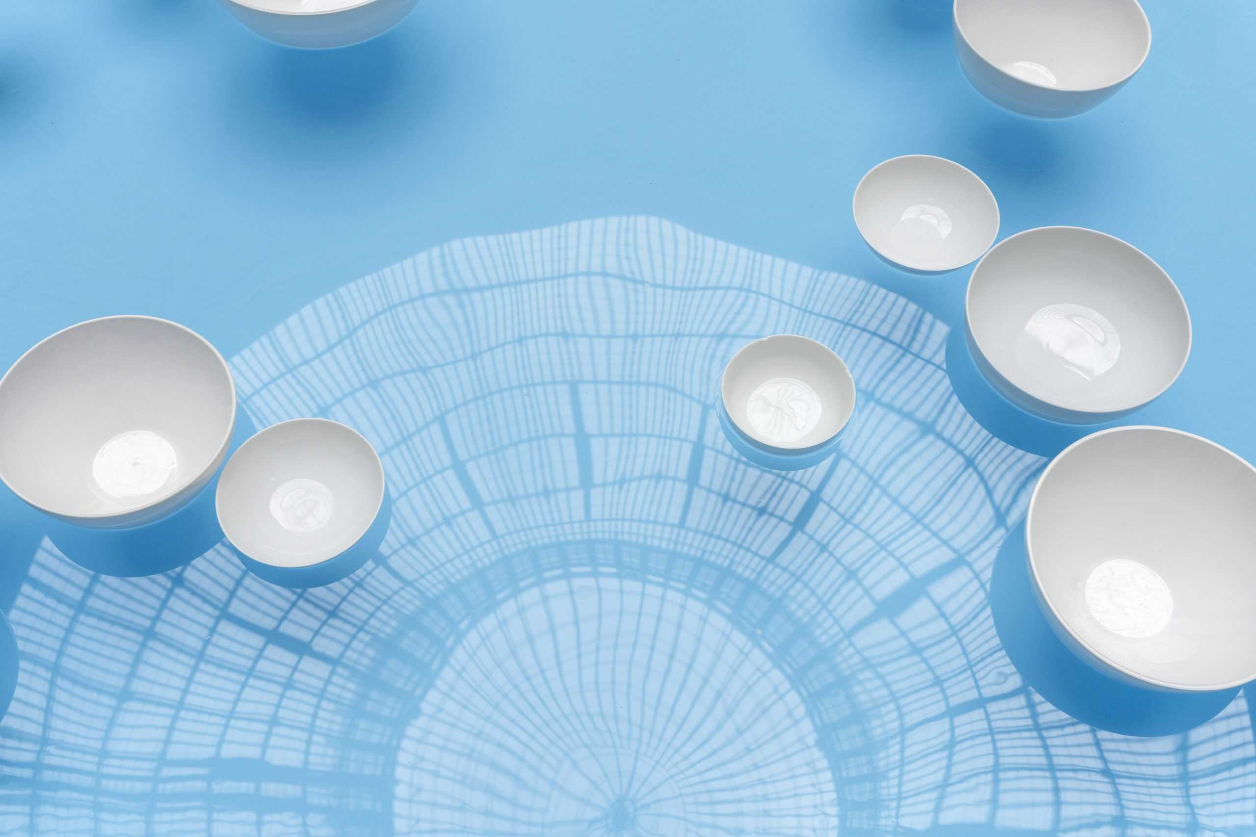 Aerial view of white porcelain bowls floating on blue water in the rotunda of Boursier-Mougenot at the Bourse de Commerce.