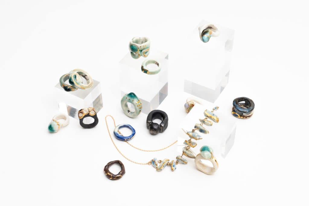 Ceramic and metal rings displayed on clear blocks and white surfaces.