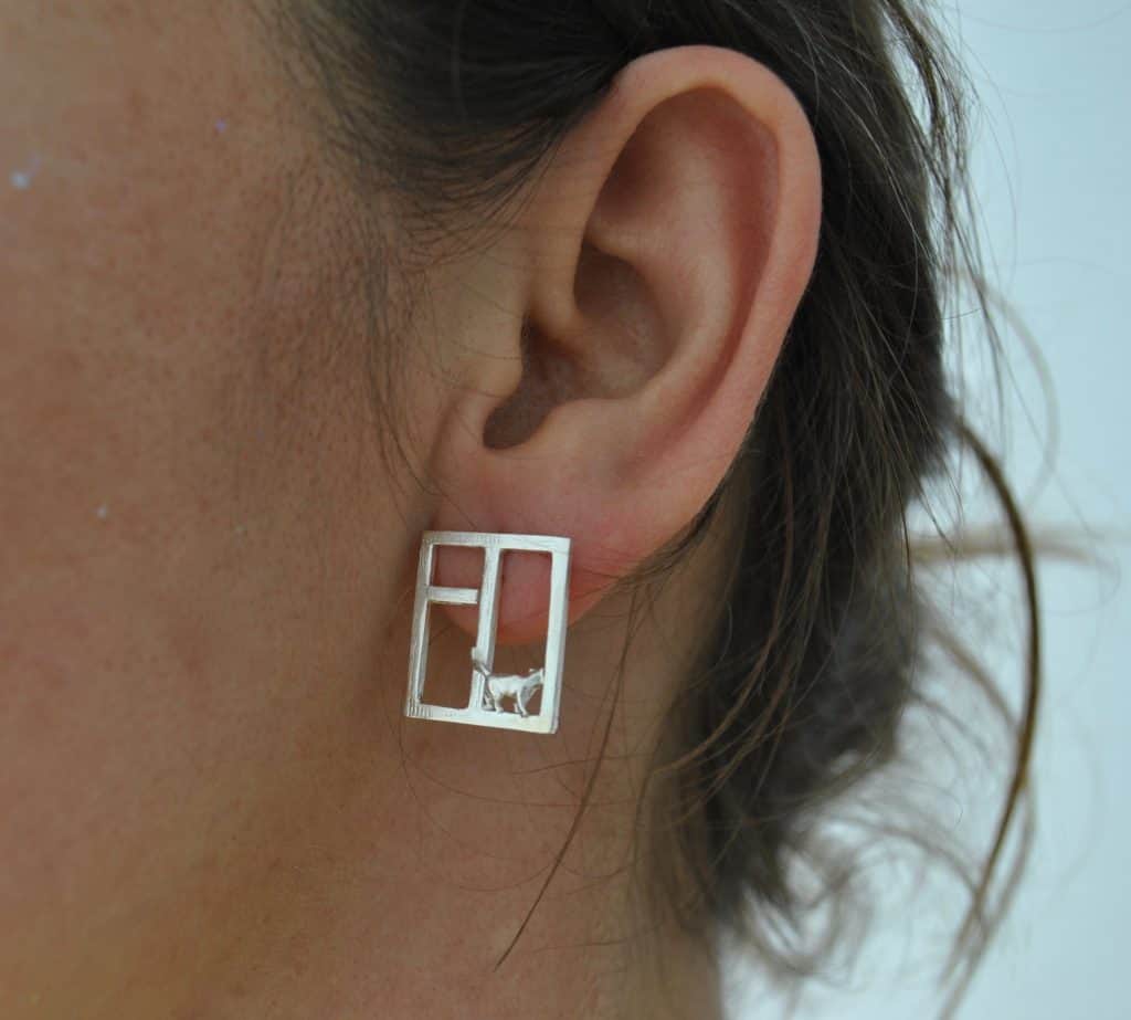 Close-up of an ear wearing geometric square earrings.