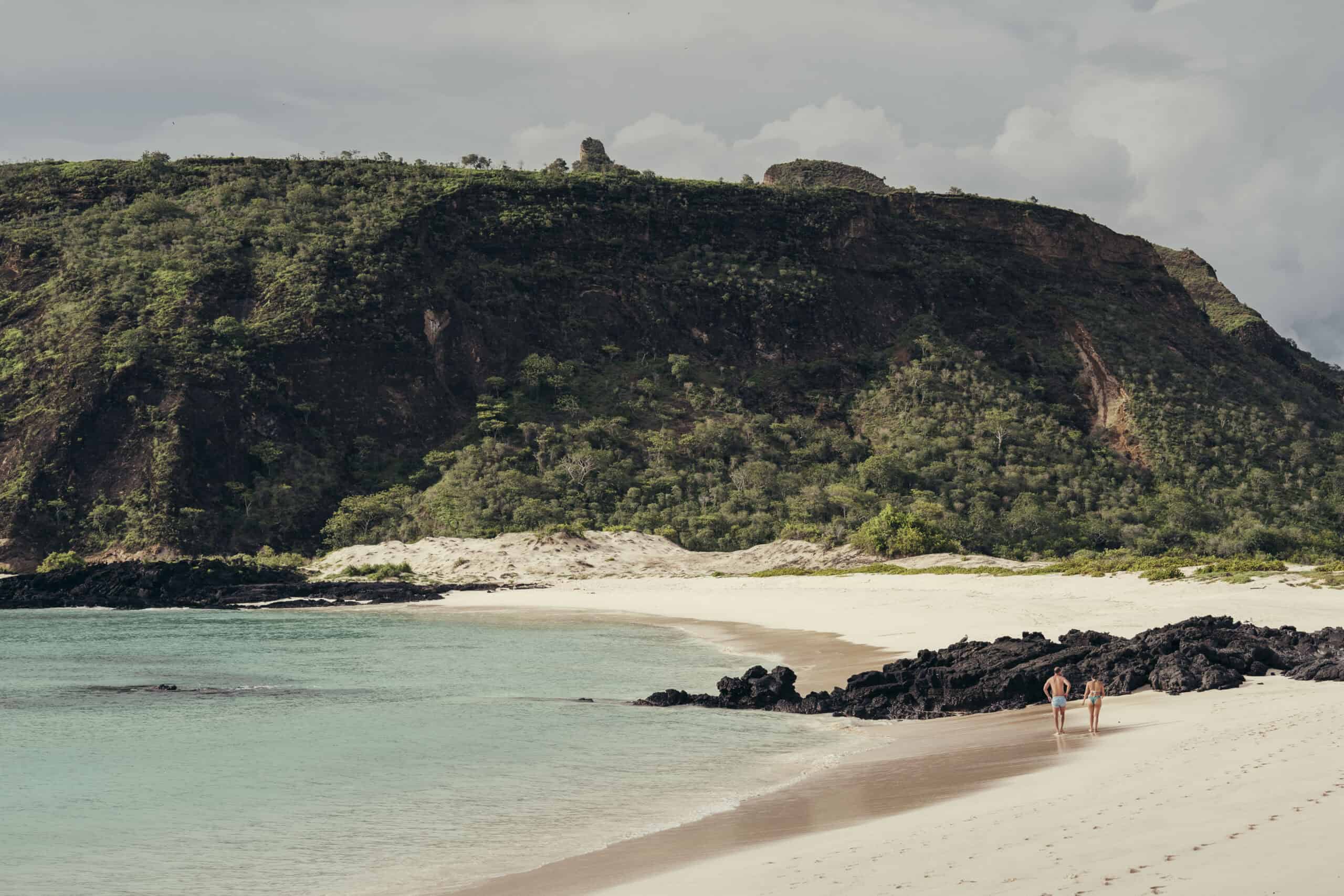 Galápagos Beach with cliffs and turquoise water, scenic coastal landscape.