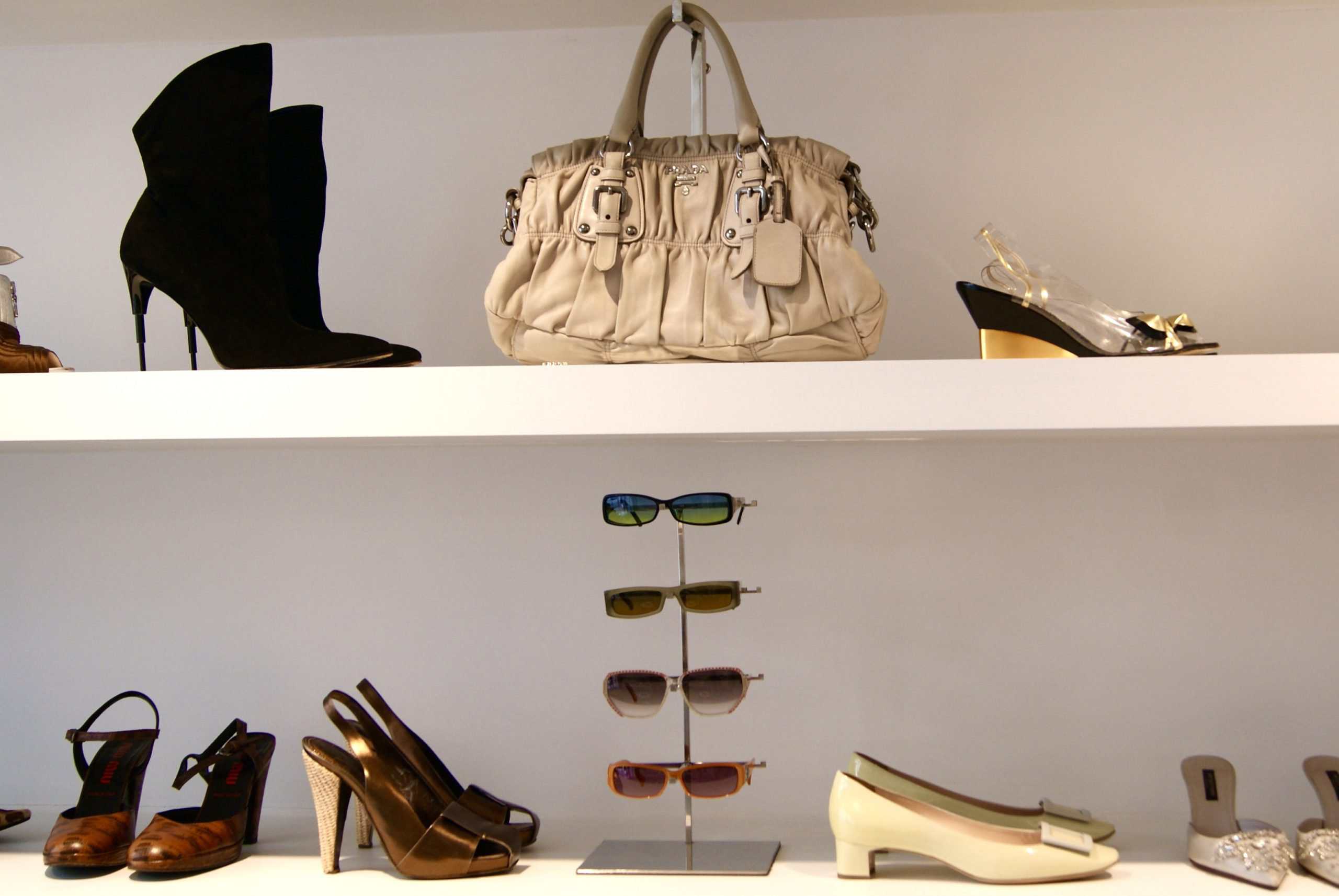 White ruffled designer handbag and neutral-toned vintage heels displayed alongside a selection of sunglasses.