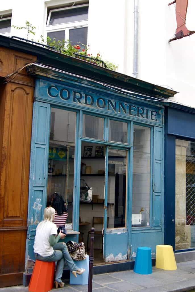 Blue facade of Boot Café Paris with vintage cobbler sign.