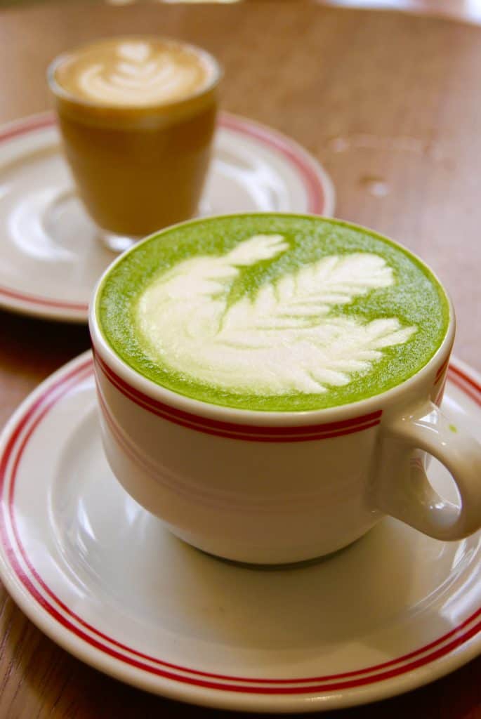 Coffee shop interior with matcha and latte, barista pouring milk