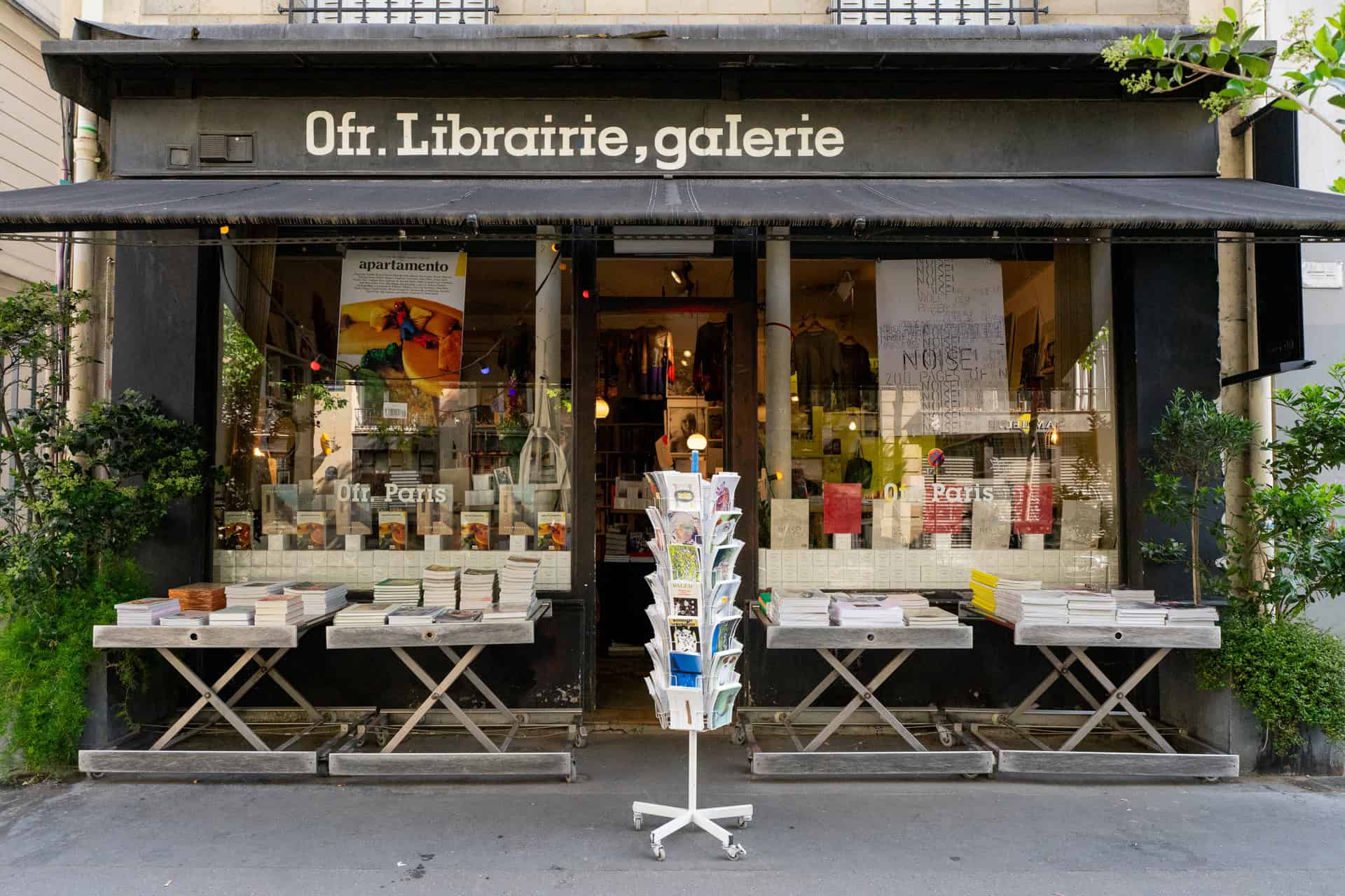 Exterior view of OFR. bookshop and gallery in Paris, with tables of books displayed outside under the awning.