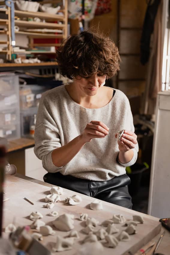 Jordane Somville working in her studio, surrounded by porcelain fragments.
