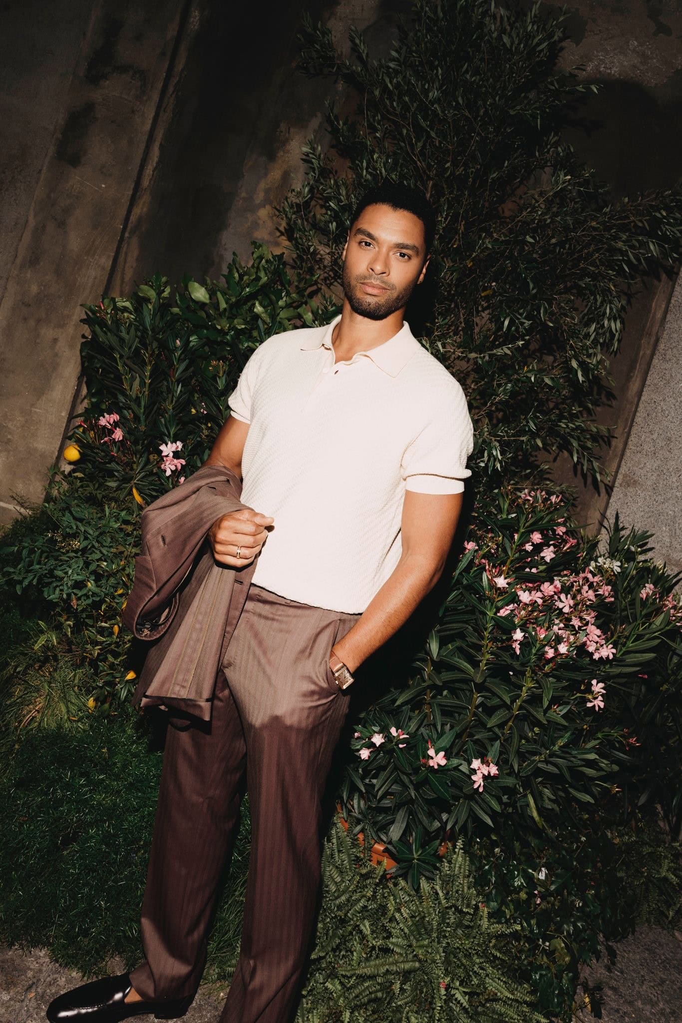 Actor Regé-Jean Page wearing a Jaeger-LeCoultre timepiece, standing in a lush night garden during the Paris launch.