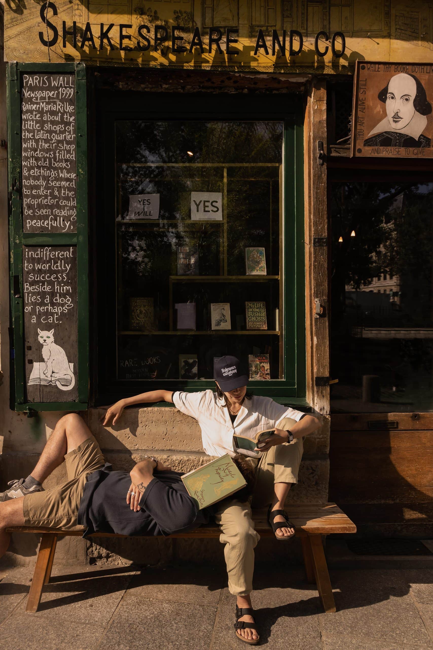 Two people reading in front of Shakespear and Co library. With a sunny weather and chill vibe. Courtesy of Shakespear and Co 
