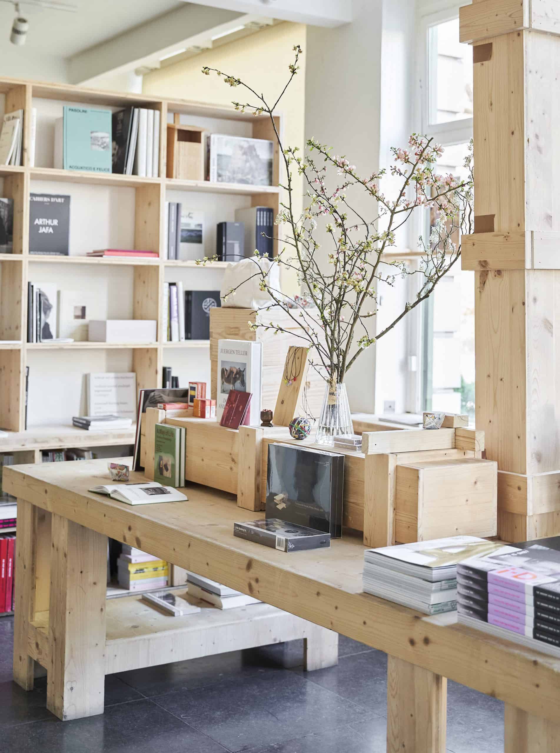 nterior of The Broken Arm concept store in Paris, featuring wooden shelves, design books, and minimalist decor.