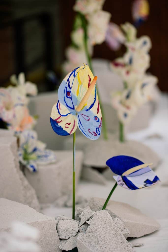  Painted anthuriums rising from cracked concrete blocks, blending floristry and art in a bridal bouquet installation.