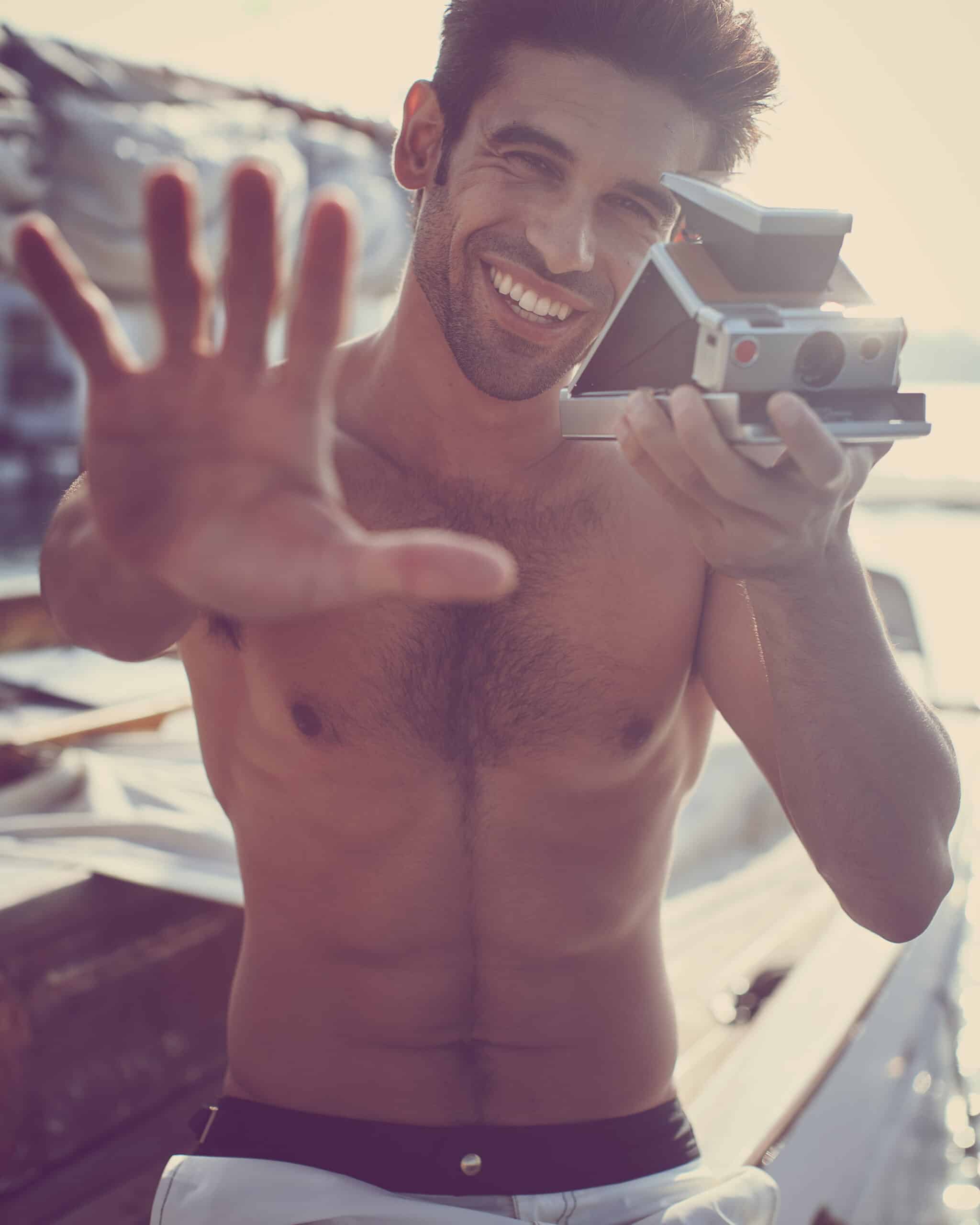 Young man taking a selfie with a vintage camera outdoors.