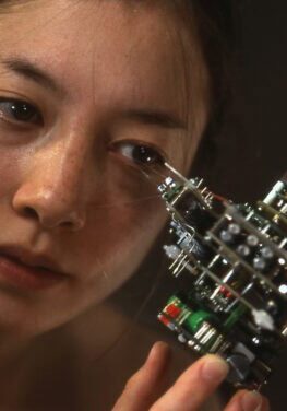 Young woman examining a complex robotic art piece at IRK Magazine exhibition.