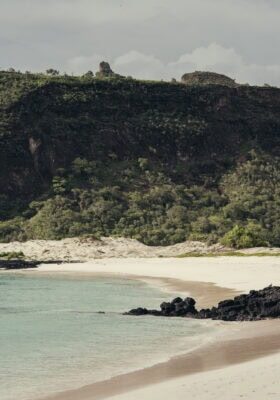 Galápagos Beach with cliffs and turquoise water, scenic coastal landscape.