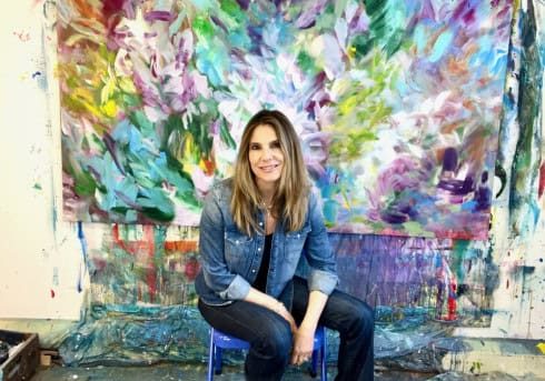 Monica Maja Richardson: artist sitting in front of one of her paintings