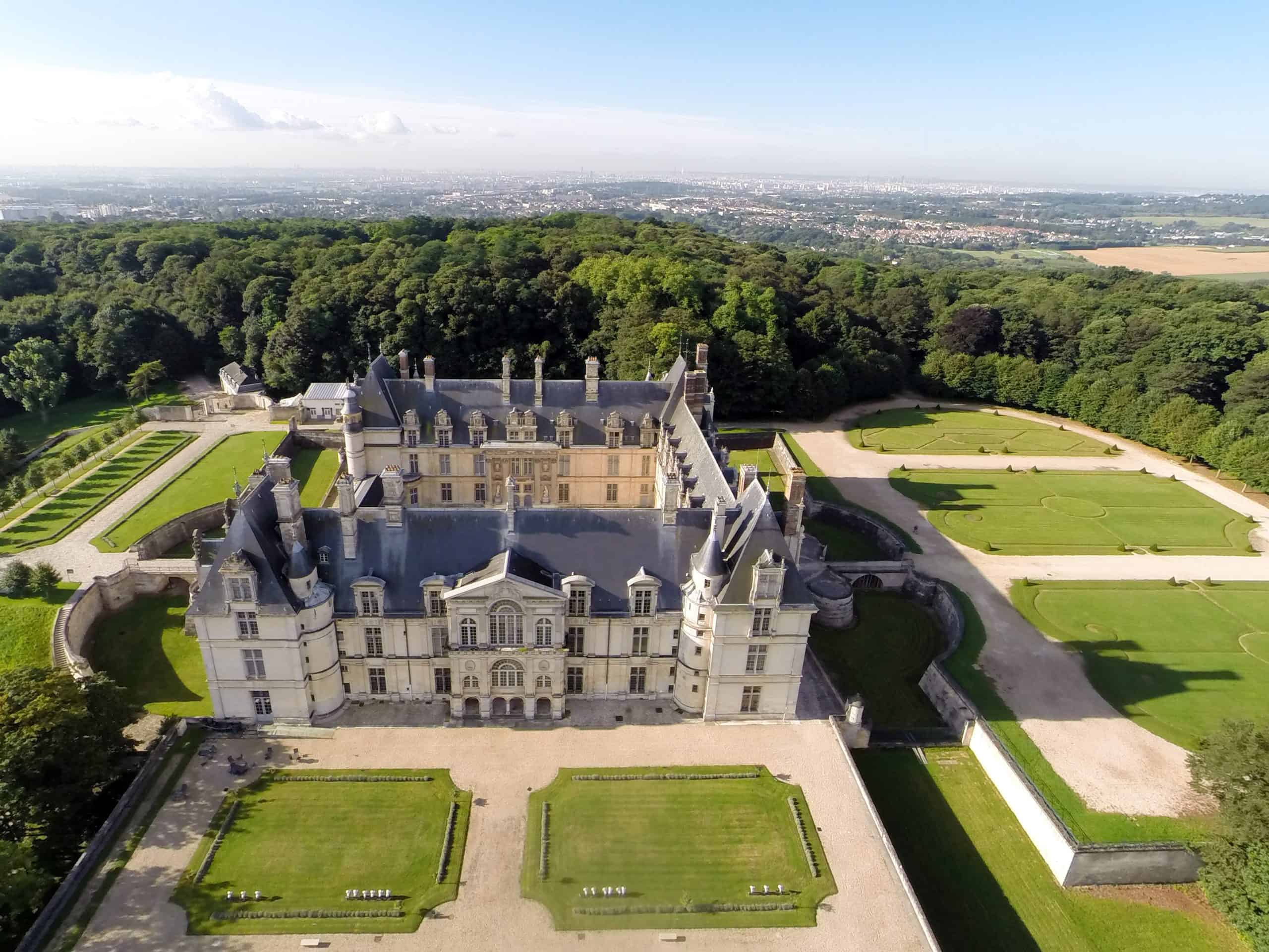 Aerial view of, a symmetrical Renaissance castle surrounded by gardens and forest. Courtesy of Musée national de la Renaissance.