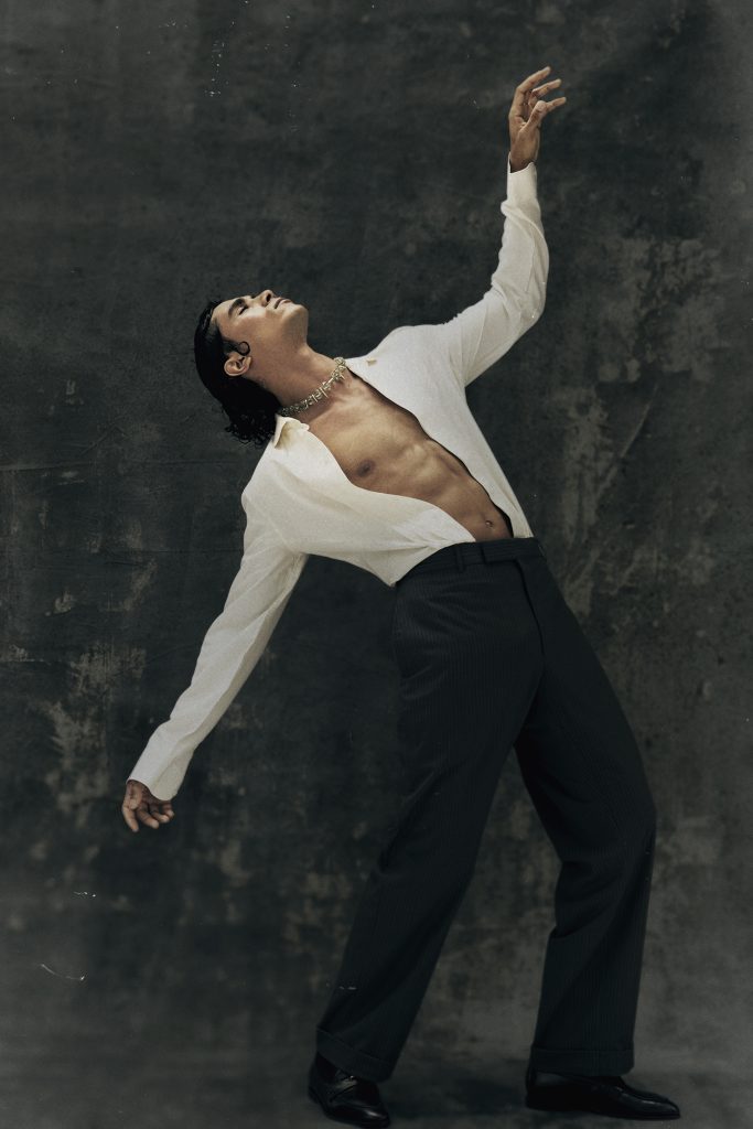 Kamal Sad performing expressive pose in open white shirt, photographed for Eternal Allure by Ben Cope.