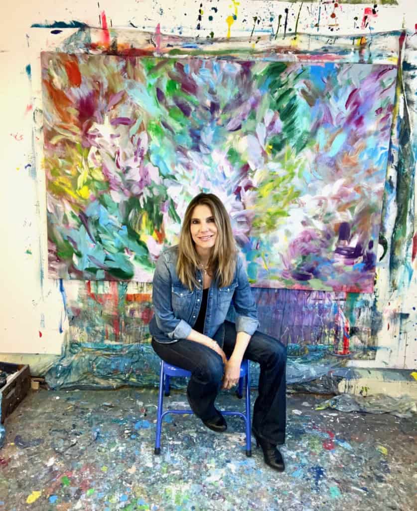 Monica Maja Richardson: artist sitting in front of one of her paintings