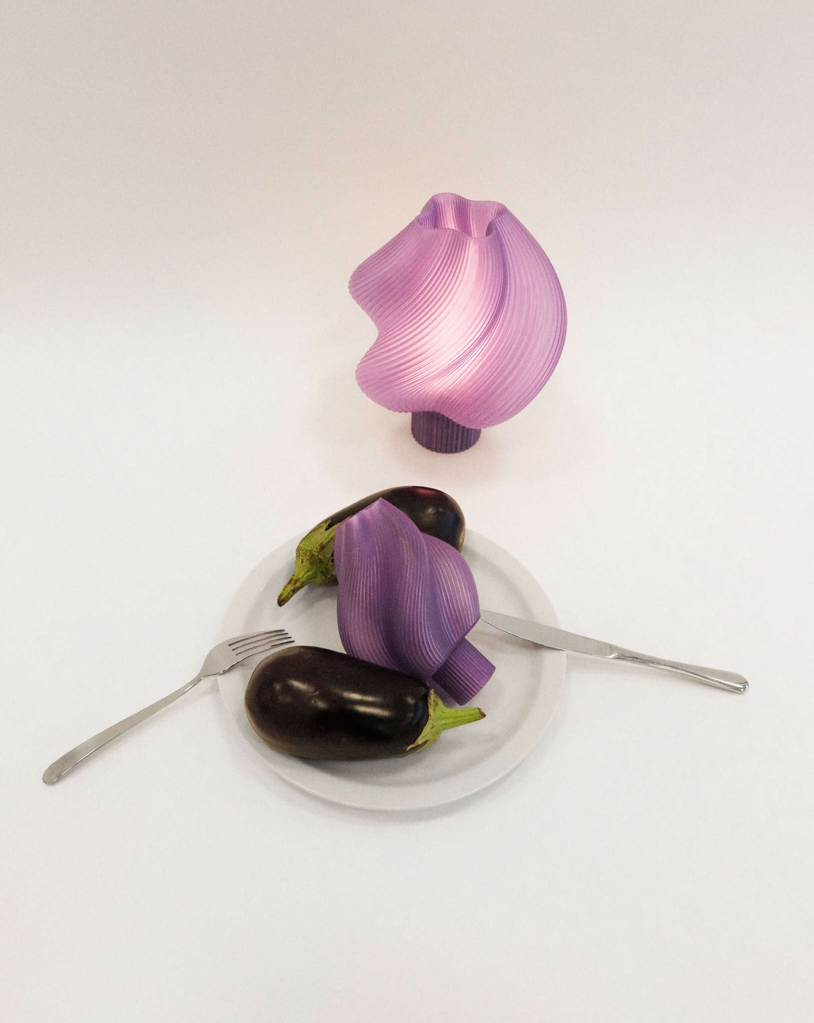 Soft Serve Lamp by Crème Atelier in pastel purple, styled with eggplants on a plate for a surreal dining setup.